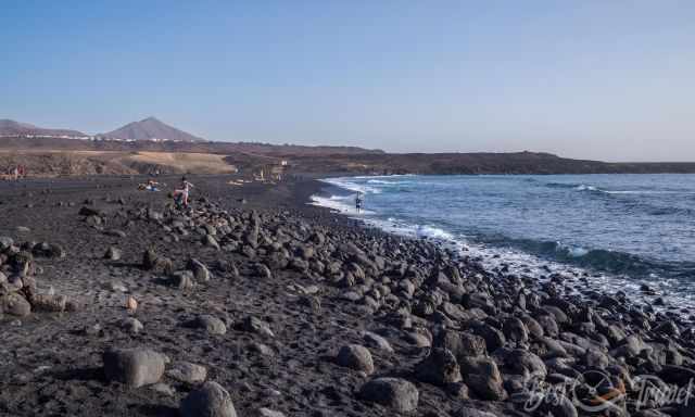 Playa de Janubio dotted with sunbathers and beach walker