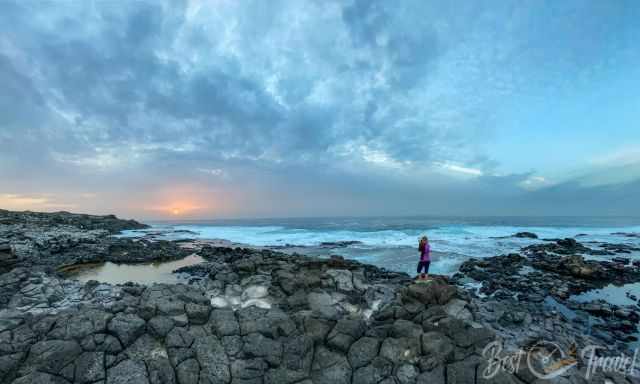 A woman taking pictures at Los Charcones Pools at sunset