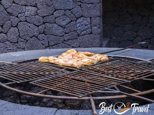 Chicken grilling over a circular volcanic vent at El Diablo Restaurant in Timanfaya National Park, using natural geothermal heat rising from the lava beneath.