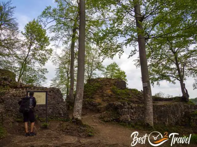 A hiker at Kichtenstein Castle ruins in front of an information board