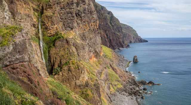 Waterfall plunges down from the cliffs at Vereda do Pesqueiro in Madeira