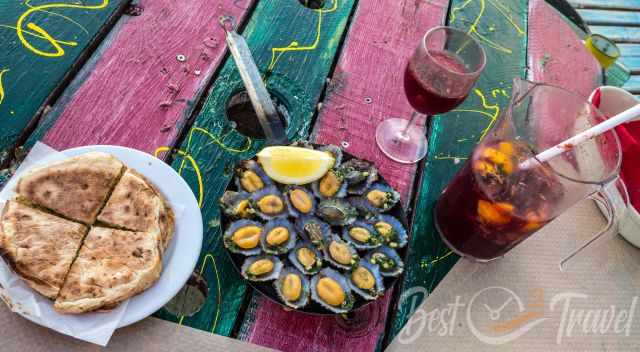 A table at the sea full of food and sangria