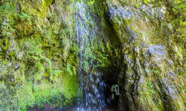 Waterfall and tunnel at the trail to Caldeirao do Inferno