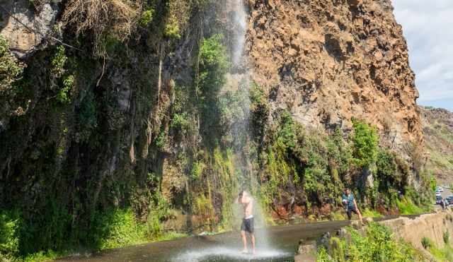 A man is taking a shower under the waterfall