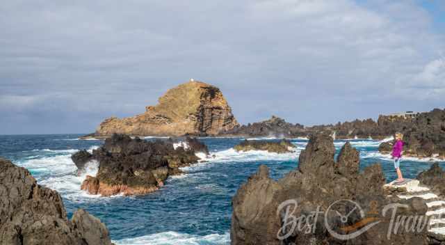 A woman standing on top of the rock at Porto Moniz Pools