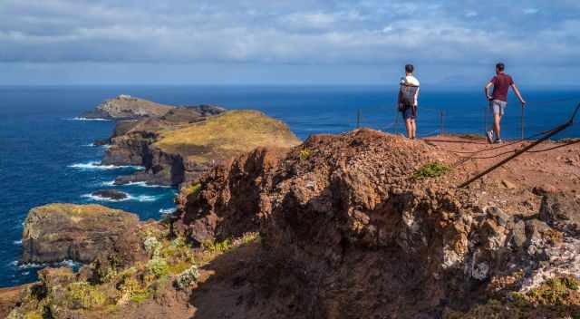 Two men at the end of the hiking trail looking to the lighthouse of Sao Lourenco.