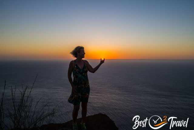 A woman "holding" the sinking sun in her hand