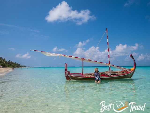 A woman in front of a boat in the azure waters.