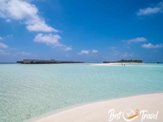 Tourists wading through ankle deep emerald green water.