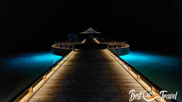 An illuminated wooden boardwalk above the sea.