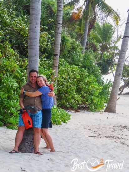 A couple leaning at a palm tree.