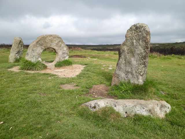 Men-an-Tol standing stones in West Penwith, including the iconic holed stone set among grassy moorland under a cloudy sky, part of a Bronze Age monument.