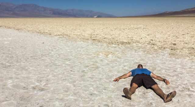 A man laying on the salt flat in the sun 