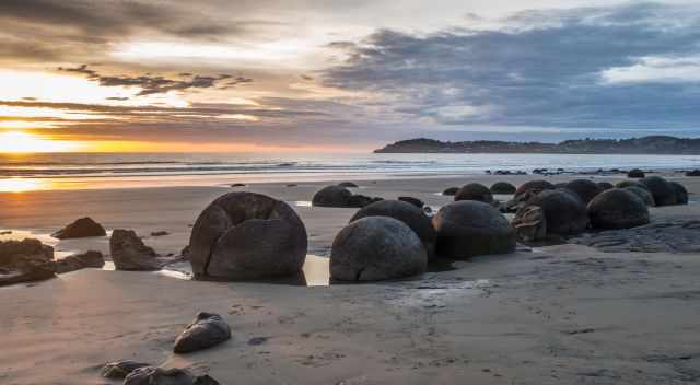 Moeraki at sunrise with a couple of clouds.