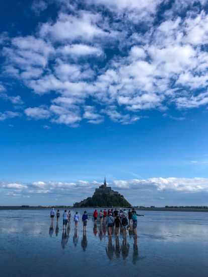 A guided tour walking through the wet sand during low tide 