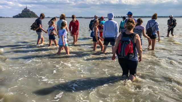 People walking around Mont Saint Michel at the incoming tide.