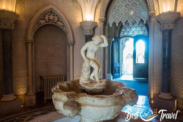A fontain with a female marble statue inside the palace.