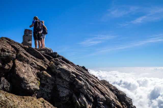 A couple standing on the summit and a marker on Pico.
