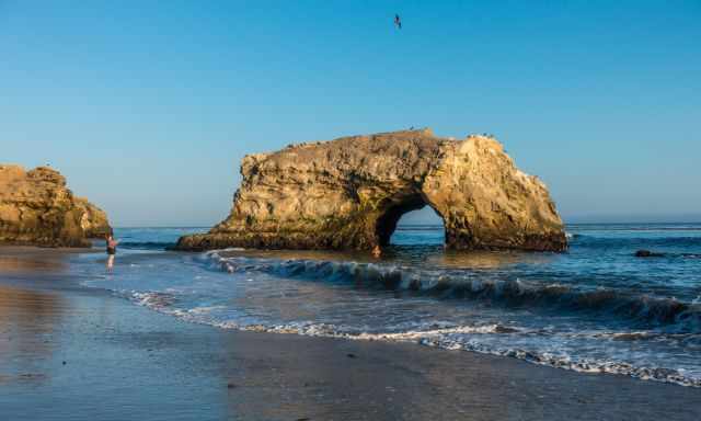 The Natural Bridge and someone swimming in the sea