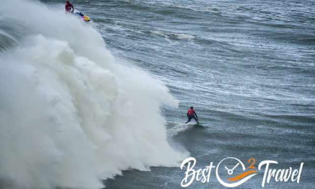 A dramatic high wave direct behind a surfer at Nazare