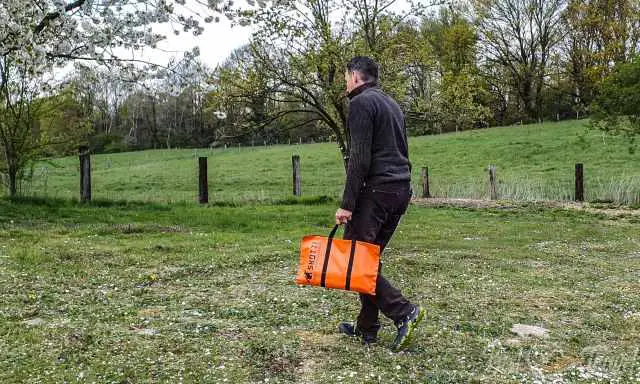 A man walking with the bbq grill on a field