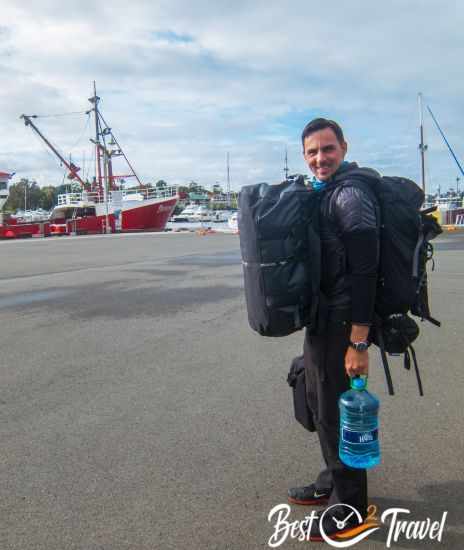 A man carrying two bags and water to the Maria Island Ferry