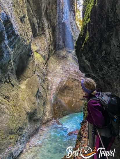 A woman looking to a waterfall at the gorge walls.