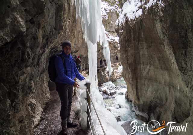 A visitor on the narrow gorge path next to immense icicles