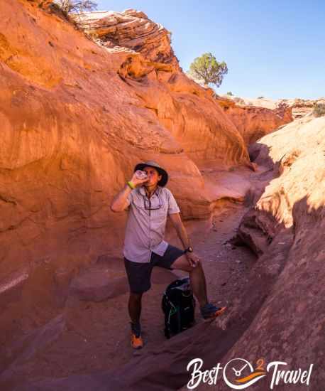 A hiker drinking water in the shade of the gulch