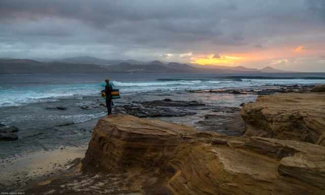 Surfer watching the sunset at Playa del Confital