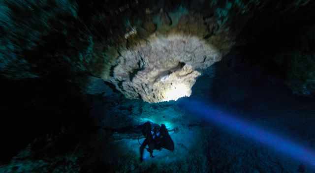 It is dark inside the cenote - only a torch light in darkness