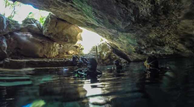 Divers inside the cenote looking out to sunlight