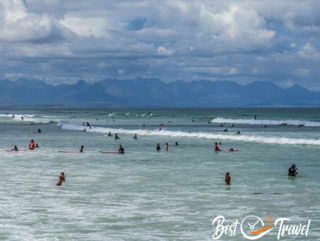 Surfer and swimmer with the mountain range in the back.