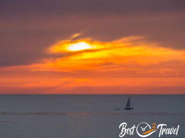 A sailing boat and the orange and yellow sunset