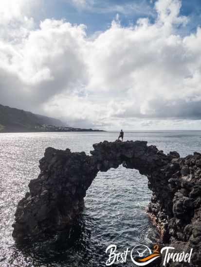 A man stands on the lava arch