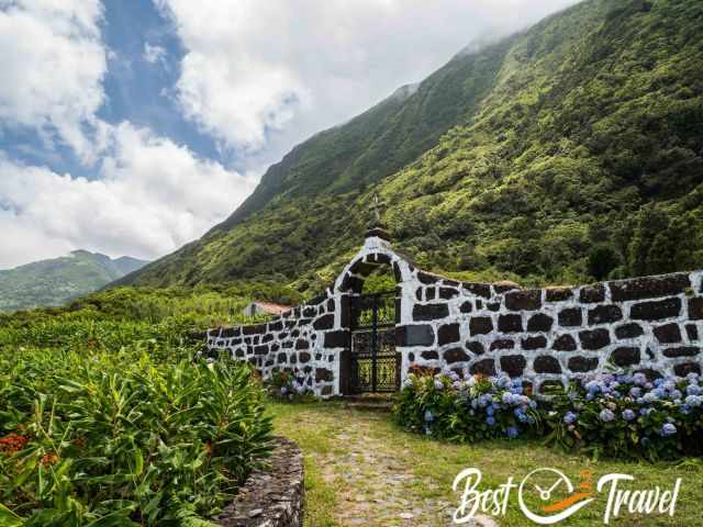 The grass‑covered path between the fajãs passes a small cemetery.