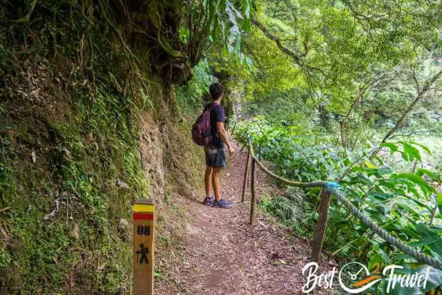 A hiker on the muddy trail which is secured with a rope.