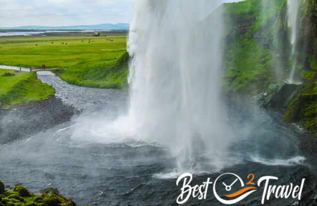 The view out of Seljalandsfoss  to visitors on a bridge to a viewpoint