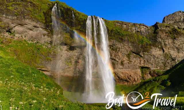 Seljalandsfoss on a sunny day with huge rainbow to the left