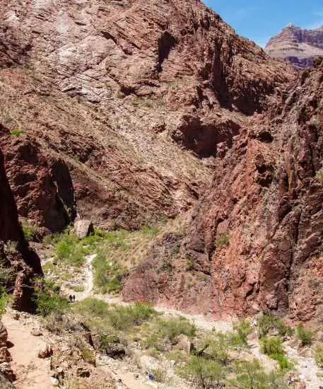 The high cliffs of the Grand Canyon and two hikers on the Bright Angel Trail