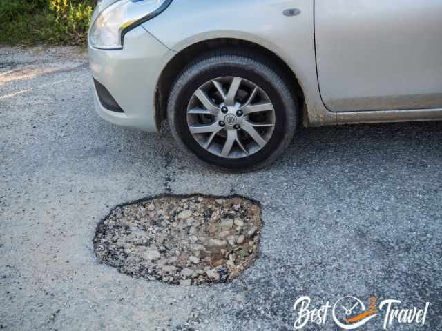 A car next to a tire big pothole