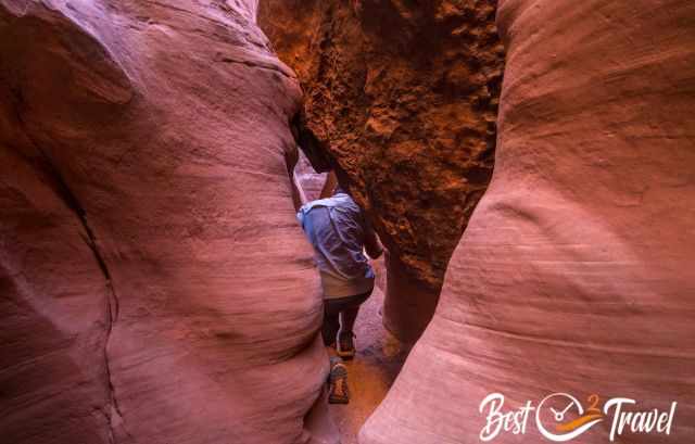 A hiker crawls through a crack.