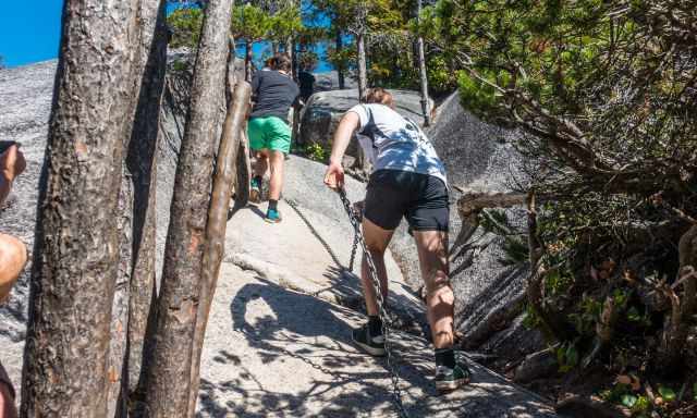 Hikers using the ropes on the slippery granite.