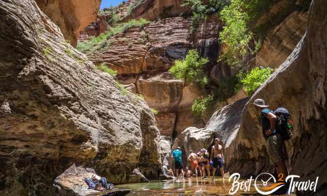 A few hikers in the cold north creek at the waterfall room.