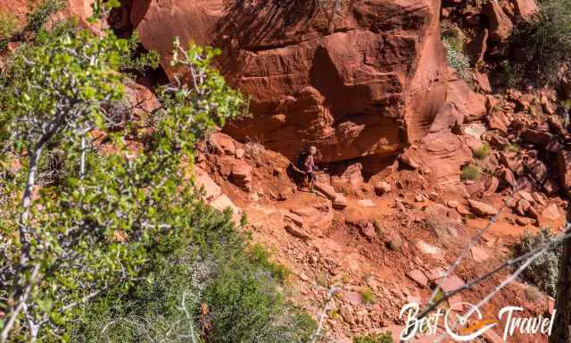 The steep trail down with loose rocks on the orange soil.