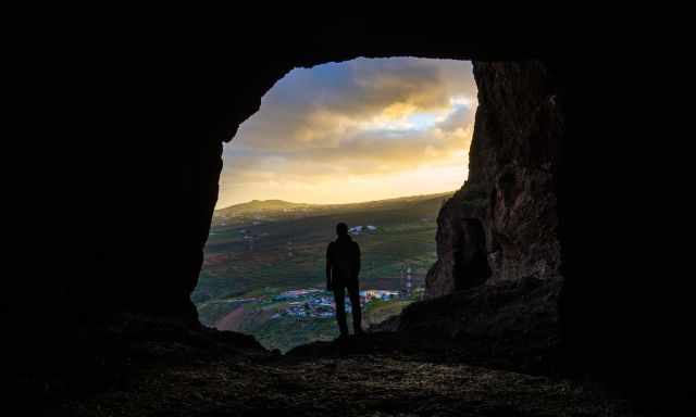 A man watching the sunset from one of the caves at Cueva de Cuatro Puertas