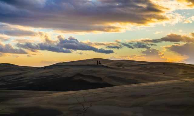 People standing on the dunes watching the sunset
