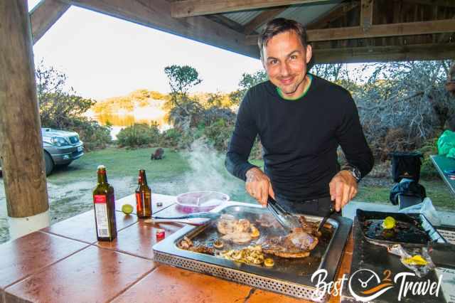 A camper preparing a meat dinner at a gas BBQ