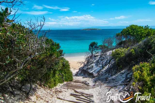 A dune trail to a white beach and turquoise sea