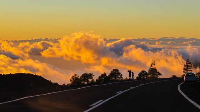 Two people watching the sunset above the clouds